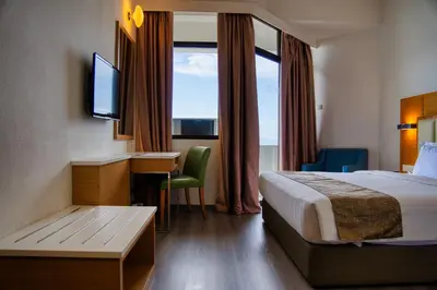 a hotel room with a bed and a desk and a television at Hotel Sentral Seaview @ ​Beachfront in George Town