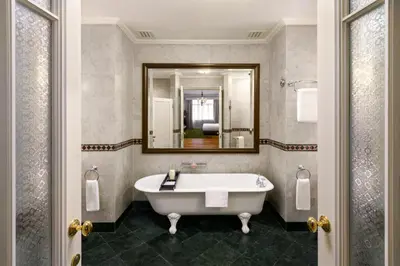 a bathroom with a tub and a mirror at Eastern & Oriental Hotel in George Town