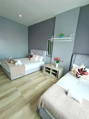 a room with two beds and a table with flowers at Octagon Premium Ipoh Town Center by Grab A Stay in Ipoh