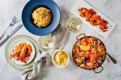 a table with plates of food and a bowl of pasta at AC Hotel by Marriott Penang in Bayan Lepas