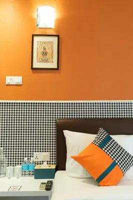 a bedroom with a bed with an orange wall at Link Hotel in George Town