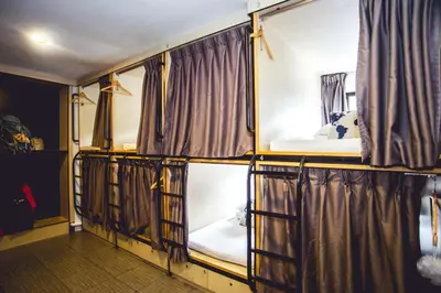a room with three bunk beds and curtains at Traveller Bunker Hostel in Cameron Highlands