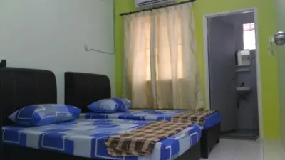 a room with two beds with blue pillows and a window at J&P Homestays House 1 in Kampar