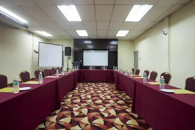 a conference room with long tables and chairs and a screen at Hotel Seri Malaysia Ipoh in Ipoh