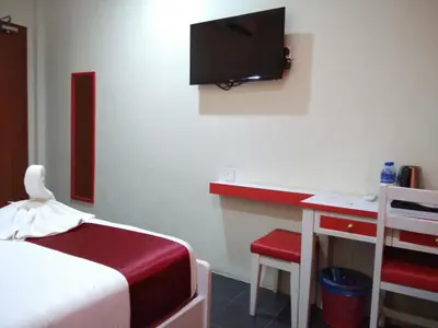 a bedroom with a bed and a desk and a tv at Pz Hotel in Kuala Kangsar