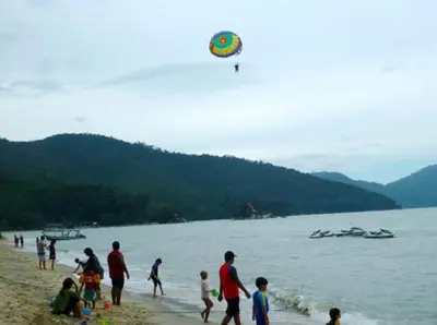 a group of people on a beach flying a kite at Pinang Beach Apartment @ Bayu Emas in Batu Ferringhi