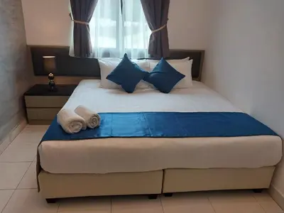 a bedroom with a bed with blue and white pillows at Sekata Apartment in Cameron Highlands