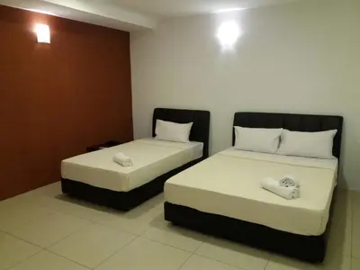 two beds in a hotel room with white sheets at T-Hotel Ipoh in Ipoh