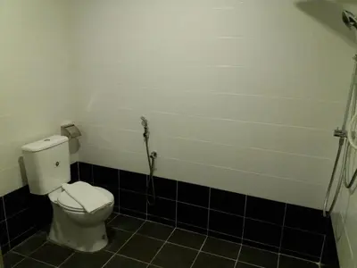 a bathroom with a white toilet and black tiles at T-Hotel Ipoh in Ipoh