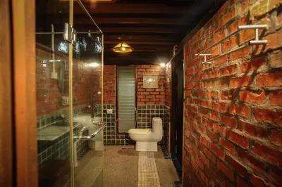 a bathroom with a toilet and a brick wall at MaliHom Private Estate in Balik Pulau