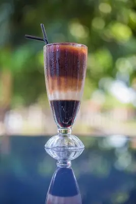a glass vase with a drink in it at Sayong Resort in Kuala Kangsar