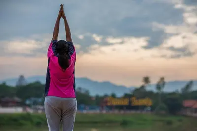 a woman doing a yoga pose in a field at Sayong Resort in Kuala Kangsar