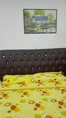 a bed with a yellow bedspread with flowers on it at Sekinchan SeaBreeze Homestay \u9002\u8015\u5e84\u6d77\u98ce\u5439\u6c11\u5bbf in Sekincan