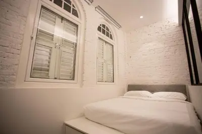 a bedroom with a white bed and two windows at The Southern Boutique Hotel in George Town