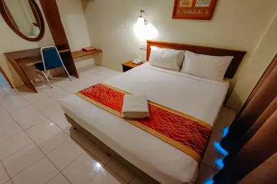 a bedroom with a bed and a desk and a chair at Virgo Batik Resort Teluk Batik Lumut in Lumut