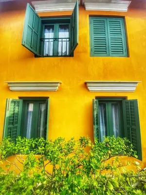 an orange building with green windows and green bushes at Yeng Keng Hotel in George Town