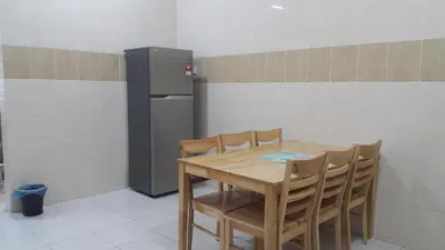 a kitchen with a table and chairs and a refrigerator at My STW Home 1 in Sitiawan