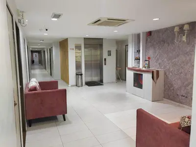 a hallway of a hospital with two red chairs and a lobby at BG Business Hotel in Bukit Mertajam