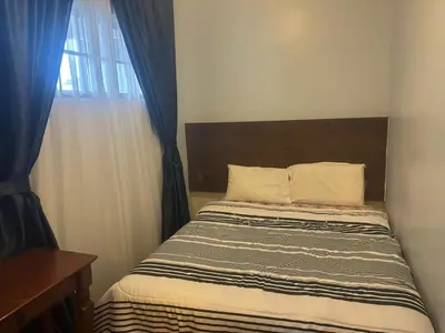 a bedroom with a bed and a window with blue curtains at Ar Rayyan Apartments Prima Villa 3D8 in Cameron Highlands