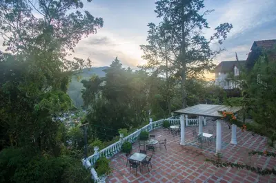 a patio with tables and chairs on a balcony at The Bala's Holiday Chalet in Cameron Highlands