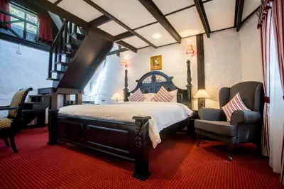 a bedroom with a large bed and two chairs at The Bala's Holiday Chalet in Cameron Highlands