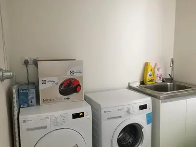 a laundry room with a washing machine and a sink at By The Sea Suite,Batu Ferringhi in Batu Ferringhi