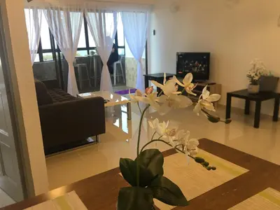 a living room with a couch and a table with flowers at The View Feringghi Executive Apartment in Batu Ferringhi