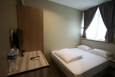 a bedroom with a bed and a table with a bottle of water at Shamrock Greenhill in Ipoh
