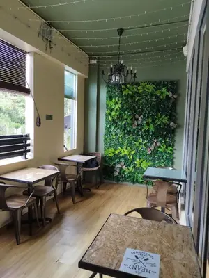 a room with tables and chairs and a green wall at Sleepbox Hotel in Cameron Highlands