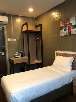 a bedroom with a white bed with a shelf on the wall at K Boutique Hotel in Teluk Intan