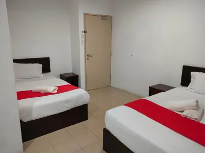 a bedroom with two beds with red and white sheets at Hotel Star Inn in Teluk Intan