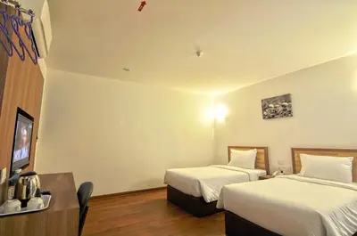 a hotel room with two beds and a television at Greencity Hotel in Sungai Petani