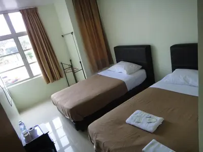 a hotel room with two beds and a window at Mines Inn Hotel in Gua Musang