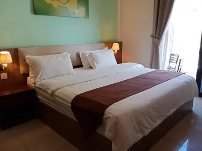 a bedroom with a large bed with white sheets and pillows at Oscar Suites Hotel in Sitiawan