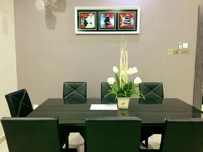 a dining room table with chairs and a vase with flowers at Bukit Banyan Homestay Sungai Petani in Sungai Petani