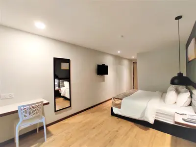 a bedroom with a bed and a desk and a chair at Apple Suites Hotel in Sitiawan