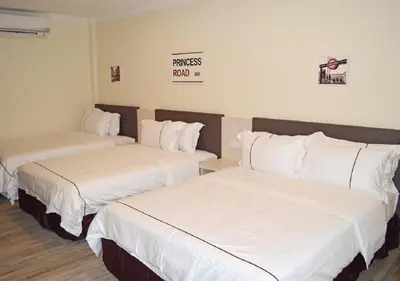 two beds in a hotel room with white sheets at Angsoka Hotel in Teluk Intan