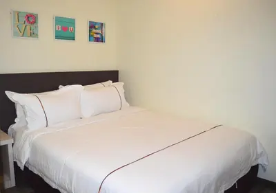 a large white bed in a room with paintings on the wall at Angsoka Hotel in Teluk Intan