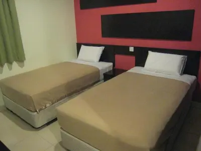two beds sitting next to each other in a room at Tropicana Inn in Sitiawan