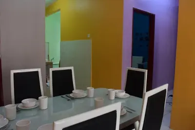 a dining room with a table with white cups and chairs at Kelly Cozy cottage in Kampar