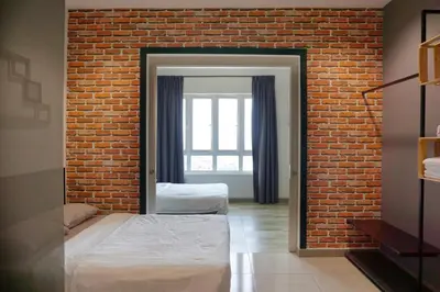 a bedroom with two beds and a brick wall at PM Octagon Ipoh Suites & Apartment 2 in Ipoh