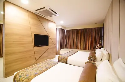 a hotel room with two beds and a tv at Hotel Sfera in Lumut
