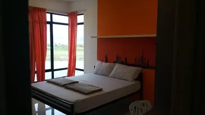 a bedroom with a bed with an orange wall and a window at The Meadow Park in Kampar