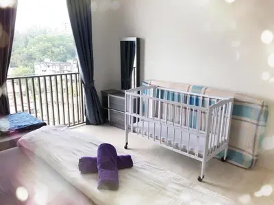 a baby crib with purple mitts on the bed in a bedroom at By The Sea BeachFront Penang in Batu Ferringhi