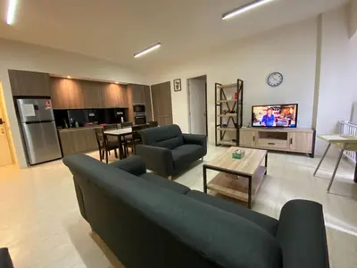 a living room with a couch and a table and a kitchen at By The Sea BeachFront Penang in Batu Ferringhi