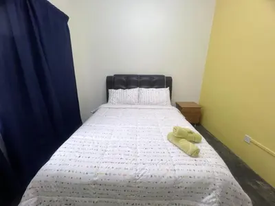 a bed with a black headboard and two towels on it at Leisure Homestay in Kampong Peruntun