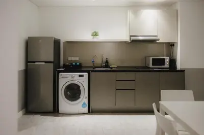 a kitchen with a washing machine and a microwave at Magazine Vista Hotel Managed by The Ascott Limited in George Town