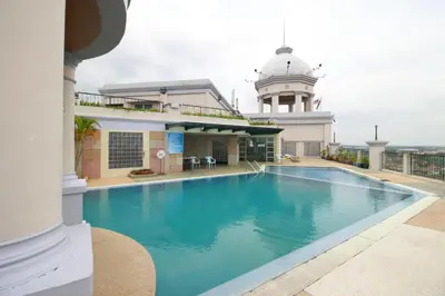 a large swimming pool in a building with a clock tower at Grand Kampar Hotel in Kampar