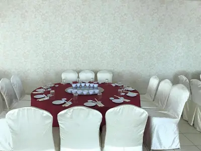 a dining room with a table and white chairs at Grand Kampar Hotel in Kampar