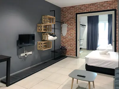 a bedroom with a bed and a tv and a brick wall at JOMSTAY Octagon Ipoh Suites in Ipoh